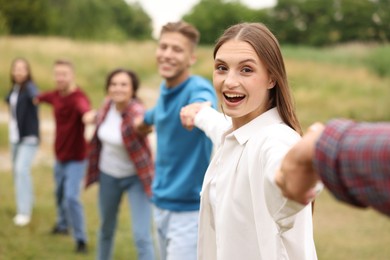 Photo of Team building. Group of happy people holding hands outdoors, selective focus
