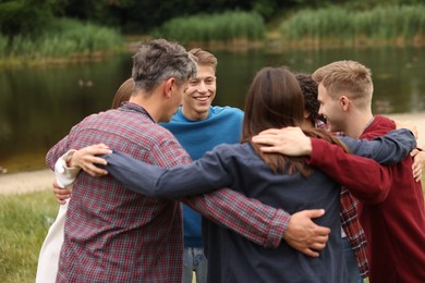 Photo of Team building. Group of happy people hugging outdoors