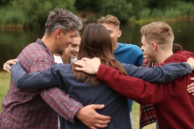 Photo of Team building. Group of happy people hugging outdoors