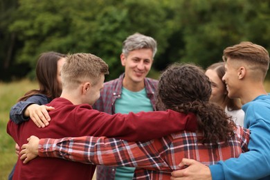 Photo of Team building. Group of happy people hugging outdoors