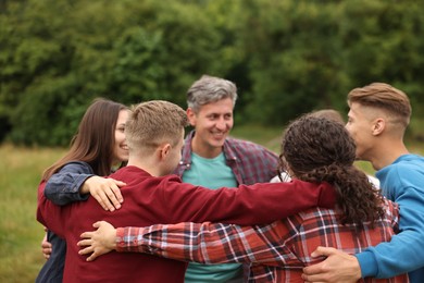 Photo of Team building. Group of happy people hugging outdoors