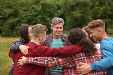 Photo of Team building. Group of happy people hugging outdoors