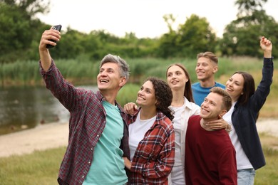 Photo of Team building. Group of happy people taking selfie outdoors