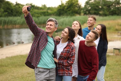 Photo of Team building. Group of happy people taking selfie outdoors