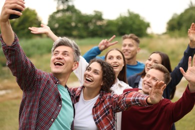 Photo of Team building. Group of happy people taking selfie outdoors