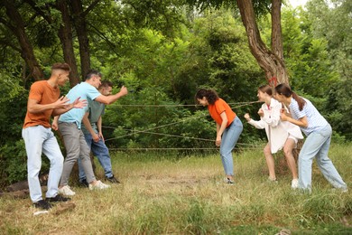 Photo of Team building. Group of happy people playing spider web game outdoors