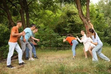 Photo of Team building. Group of happy people playing spider web game outdoors