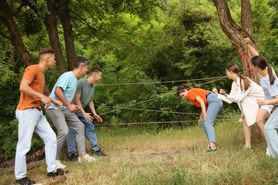 Photo of Team building. Group of happy people playing spider web game outdoors