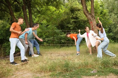Photo of Team building. Group of happy people playing spider web game outdoors