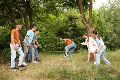 Photo of Team building. Group of happy people playing spider web game outdoors