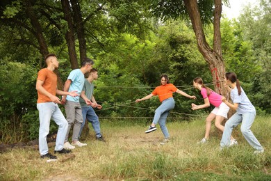 Photo of Team building. Group of happy people playing spider web game outdoors