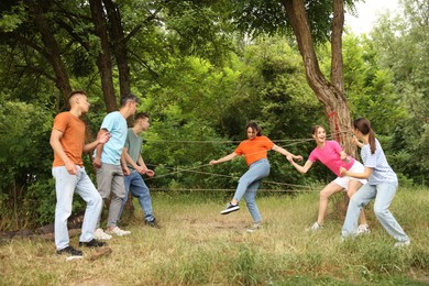 Photo of Team building. Group of happy people playing spider web game outdoors