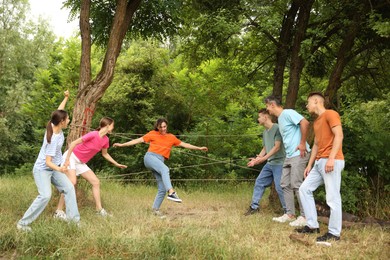 Photo of Team building. Group of happy people playing spider web game outdoors