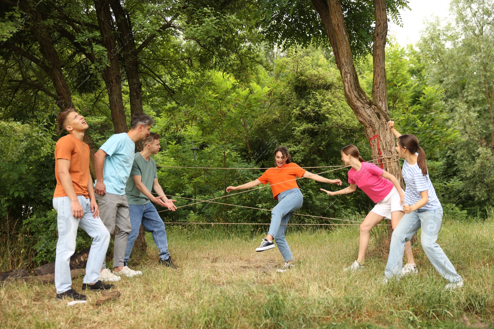 Team building. Group of happy people playing spider web game outdoors Photo of Team building. Group of happy people playing spider web game outdoors