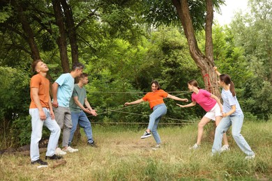 Photo of Team building. Group of happy people playing spider web game outdoors