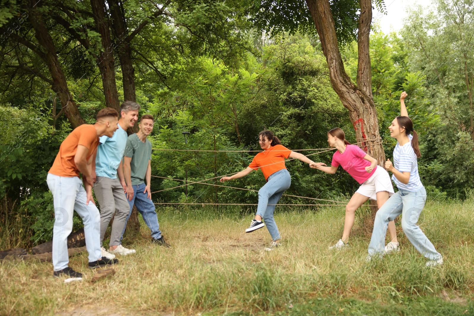 Photo of Team building. Group of happy people playing spider web game outdoors