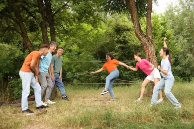 Photo of Team building. Group of happy people playing spider web game outdoors
