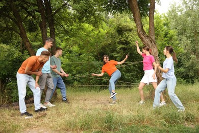 Photo of Team building. Group of happy people playing spider web game outdoors