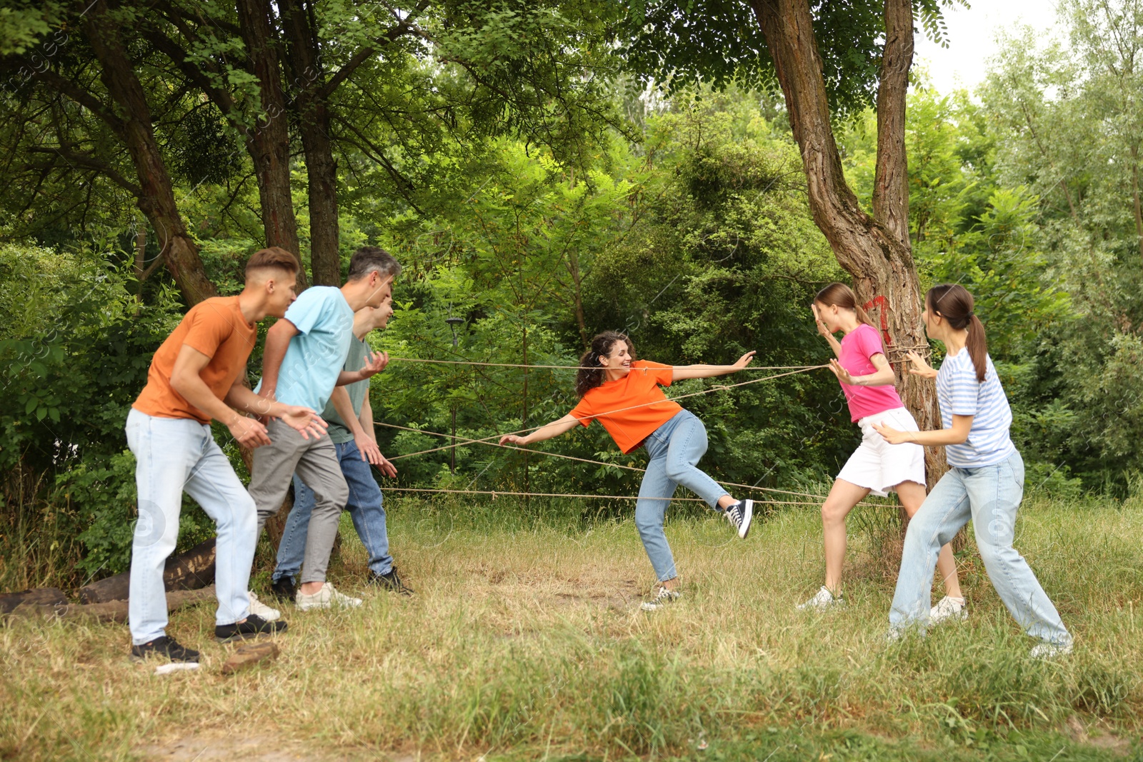 Photo of Team building. Group of happy people playing spider web game outdoors