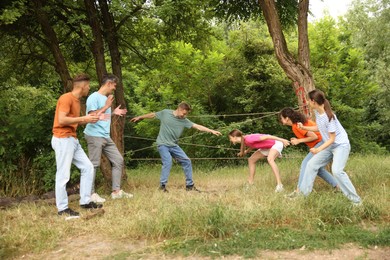 Photo of Team building. Group of happy people playing spider web game outdoors