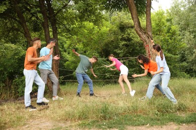 Photo of Team building. Group of happy people playing spider web game outdoors