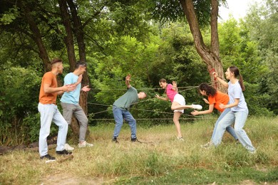 Photo of Team building. Group of happy people playing spider web game outdoors