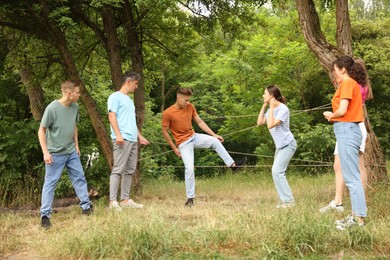 Photo of Team building. Group of happy people playing spider web game outdoors