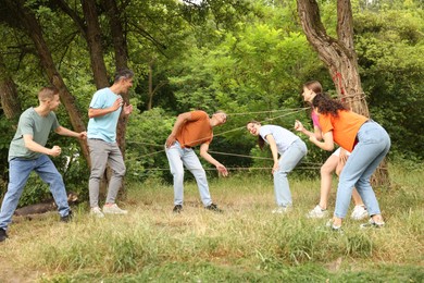 Photo of Team building. Group of happy people playing spider web game outdoors