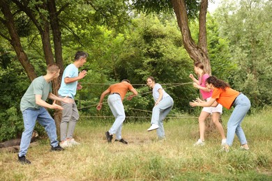 Photo of Team building. Group of happy people playing spider web game outdoors