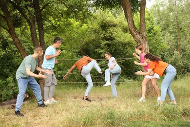 Photo of Team building. Group of happy people playing spider web game outdoors