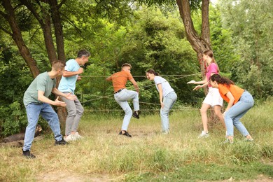 Photo of Team building. Group of happy people playing spider web game outdoors