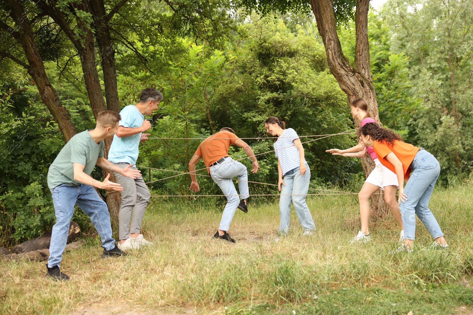 Photo of Team building. Group of happy people playing spider web game outdoors