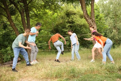 Photo of Team building. Group of happy people playing spider web game outdoors