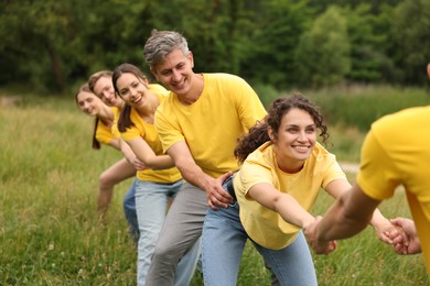Photo of Team building. Group of happy people holding hands outdoors