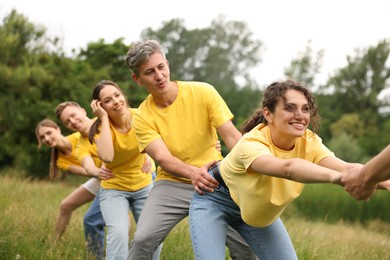 Photo of Team building. Group of happy people holding hands outdoors