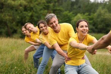 Photo of Team building. Group of happy people holding hands outdoors