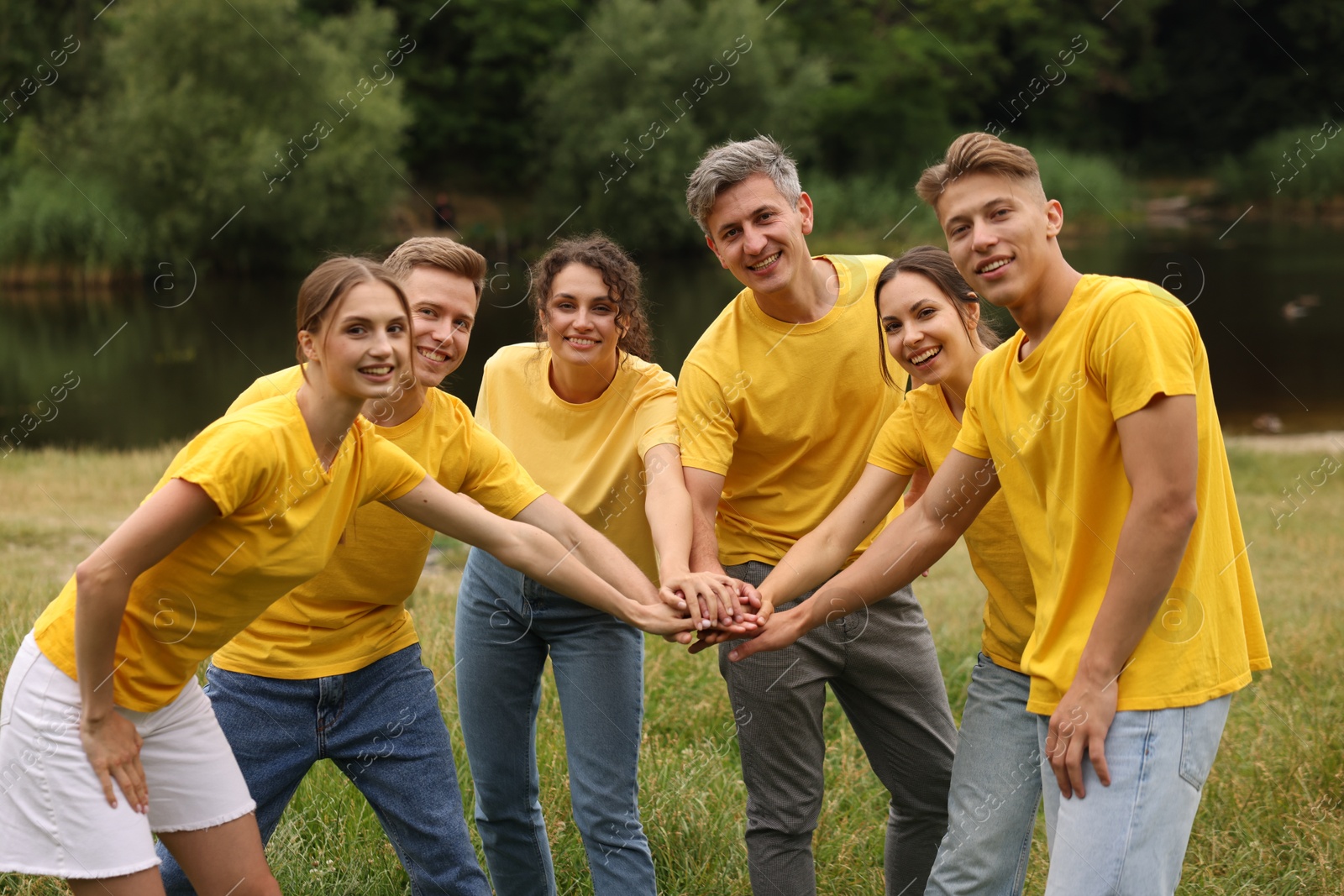 Photo of Team building. Group of happy people joining hands outdoors