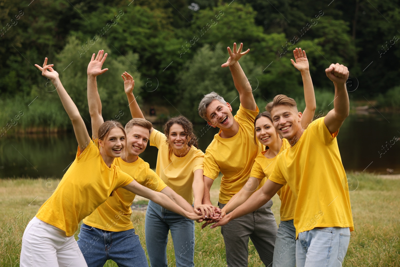 Photo of Team building. Group of happy people joining hands outdoors