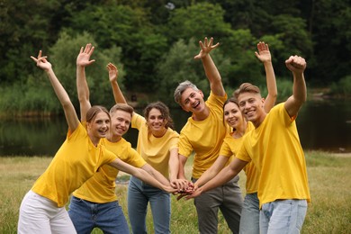 Photo of Team building. Group of happy people joining hands outdoors