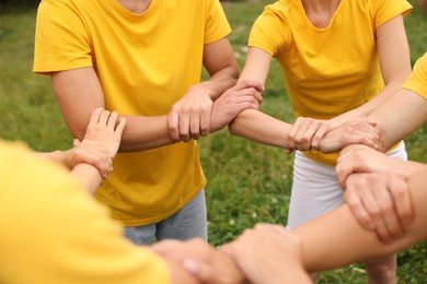 Photo of Team building. Group of people joining hands outdoors, closeup