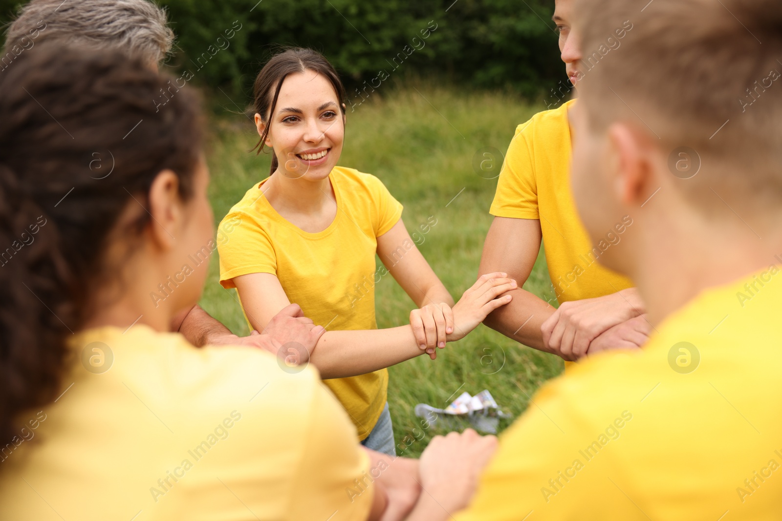 Photo of Team building. Group of happy people joining hands outdoors