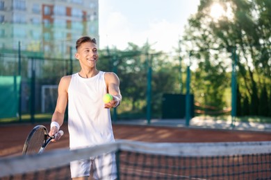 Photo of Young man playing tennis at court on sunny day. Space for text