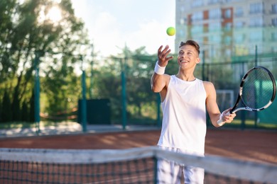Photo of Young man playing tennis at court on sunny day. Space for text