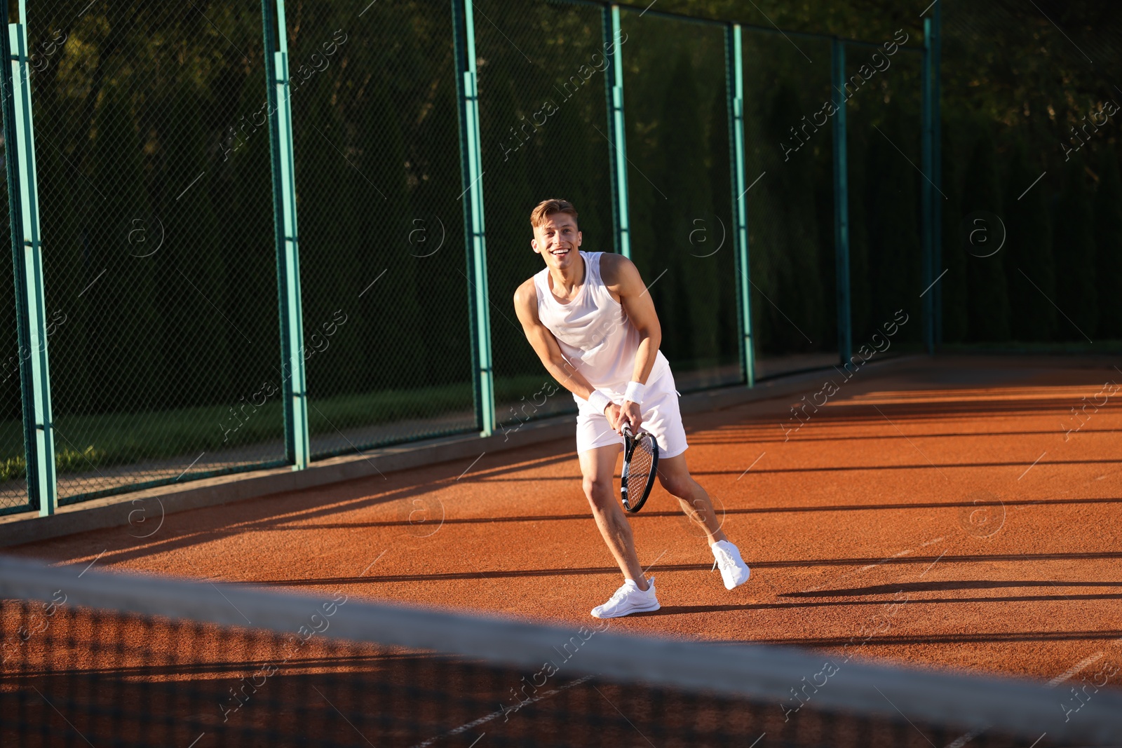 Young man playing tennis at court on sunny day Photo of Young man playing tennis at court on sunny day
