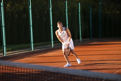 Photo of Young man playing tennis at court on sunny day