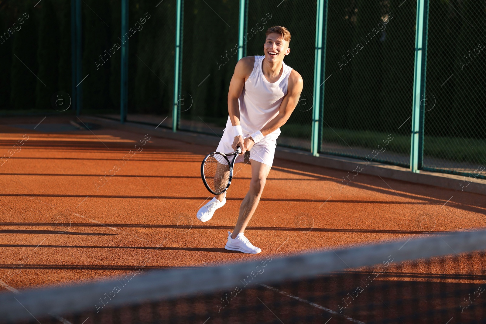 Young man playing tennis at court on sunny day Photo of Young man playing tennis at court on sunny day