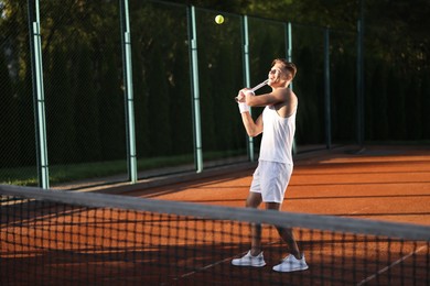 Photo of Young man playing tennis at court on sunny day. Space for text