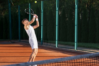 Photo of Young man playing tennis at court on sunny day. Space for text