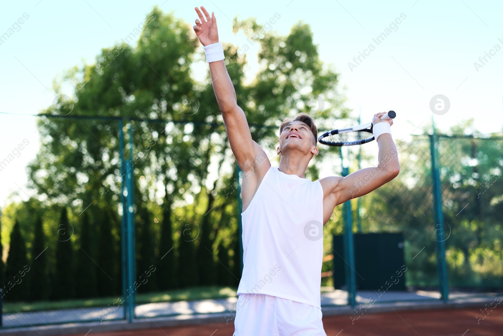Young man playing tennis at court on sunny day Photo of Young man playing tennis at court on sunny day