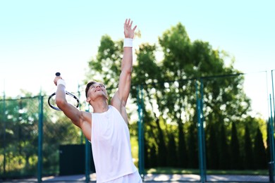 Photo of Young man playing tennis at court on sunny day. Space for text